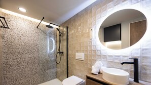 A modern bathroom with a freestanding shower, a toilet, a sink with a round mirror, and a towel rack. - Apartamento Turístico Royal (Cartagena)