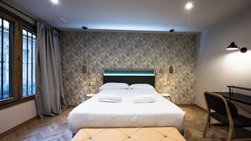 A modern bedroom with a large bed, a desk, and a chair.