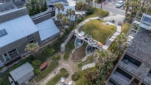 An aerial view of a residential area with modern architecture, including a house with a curved balcony and a circular outdoor seating area.