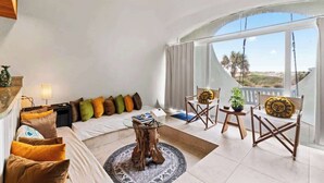 A modern living room with a sofa, chairs, a coffee table, and a large window offering a view.