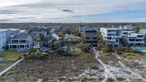 A coastal residential area with modern houses, a central building with a unique design, and a clear view of the ocean.