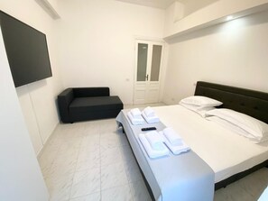 Een hotelkamer met een bed, een bank, een televisie en een deur.