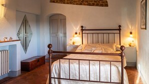 A bedroom with a wooden bed, two bedside lamps, a stone wall, and a white door. - Villa Il Colle di Sotto - Imagine a place just for you (Toscana)