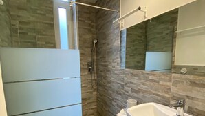 Et moderne badeværelse med bruser, toilet og håndvask.
