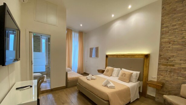 Habitación de hotel con una cama grande, un escritorio, un televisor y una pared de acento de piedra.