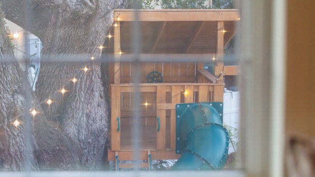 A wooden structure with a balcony, a wheel, and a green cylindrical object.
