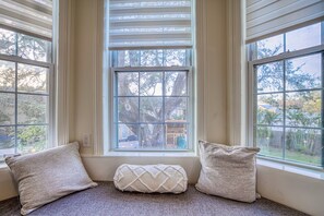 Relax in comfort with a view of the tree-lined yard from this cozy room, featuring a large window with lighting and plush carpeting.