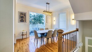 A dining area with a wooden table and chairs, a chandelier, and a staircase.