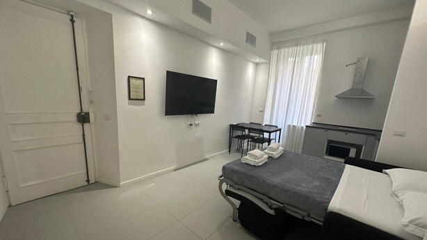 Een moderne slaapkamer met een bed, een bureau, een flatscreen televisie en een open haard.