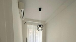 Een woonkamer met een bruine bank, een statieflamp en een luchtverkoeler aan het plafond.