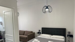 Een moderne slaapkamer met een bed, een bank en een bijzondere hanglamp.