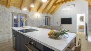 A spacious kitchen with a large island, stone walls, wooden beams, and modern appliances. - Stone House Trogir - with jacuzzi (Trogir)