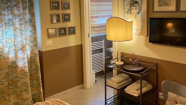 A hotel room with a bed, a desk with a lamp, a chair, and a TV. - Le Stanze dei Cardinali guest house c1 (ROMA)