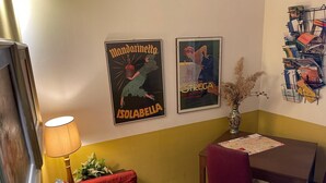 A dining area with a table, chairs, a vase with dried plants, and two framed posters on the wall. - Le Stanze dei Cardinali guest house c1 (ROMA)