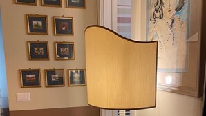 Una habitación con una mesa de vidrio, una lámpara y cuadros en la pared.