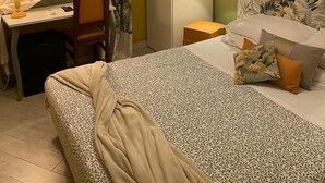 Een hotelkamer met een bed, een bureau, een stoel, een nachtkastje en een bloemenprint op de muur.