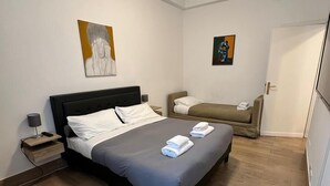 Ein Schlafzimmer mit Bett, Nachttisch, Lampe und Kunstwerken an den Wänden.