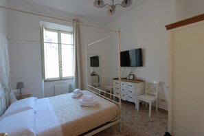 A four-poster bed with a white canopy, a television mounted on the wall, a wooden dresser, and a window with curtains. - Art Atelier San Pietro c1 (Roma)