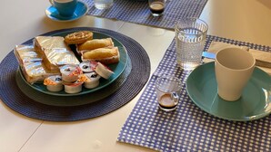 A table with a plate of sandwiches, waffles, and condiments, along with cups and glasses of beverages.