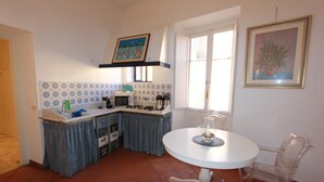 A compact kitchen with a dining area, featuring a tiled backsplash, a microwave, a sink, and a small table with a chair. - Art Atelier San Pietro app int loc turistica (Roma)
