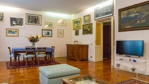 Una sala de estar con comedor, muebles de madera, televisor y varias fotografías enmarcadas en las paredes.