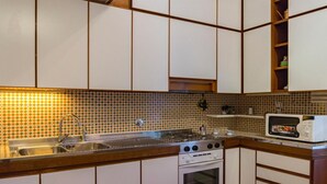 Una cocina compacta con estufa a gas, horno, microondas y un lavamanos con grifo.