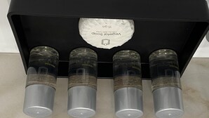 A black box containing four transparent bottles with labels, one of which is partially visible.