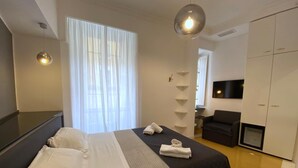 A modern hotel room with a large bed, a wardrobe, a television, and a desk.
