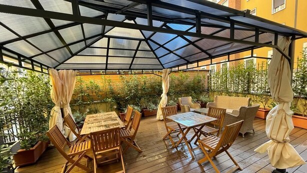 A covered outdoor patio with wooden furniture and potted plants.