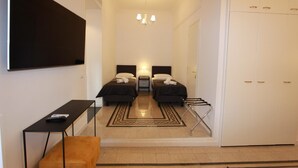 A hotel room with two beds, a desk, a chair, a TV, and a wardrobe. - Art Atelier Risorgimento guest house c2 (ROMA)