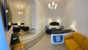 A hotel room with a bed, bedside tables, a TV, a sofa, and a chandelier. - Art Atelier Risorgimento guest house c2 (ROMA)