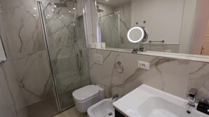 A modern bathroom with a glass-enclosed shower, a toilet, a bidet, and a sink with a mirror above. - Art Atelier Risorgimento guest house c2 (ROMA)
