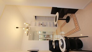 A modern dining area with a minimalist design, featuring a central table with a black and white color scheme, a chandelier, and a large mirror on the wall. - Art Atelier Risorgimento guest house c2 (ROMA)