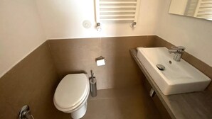 Un baño con inodoro, lavamanos y espejo.