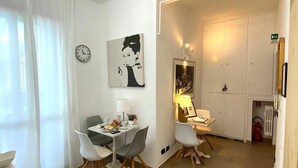 Un comedor con candelabro, paredes blancas, un reloj y un cuadro.