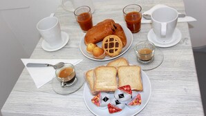 Una mesa blanca con una bandeja de pasteles, una tetera y tazas.