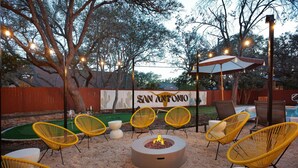 An outdoor patio with yellow chairs, a fire pit, and a pool area. - Giddy Up Getaway: Pool, Hot Tub & Family Fun! (San Antonio)