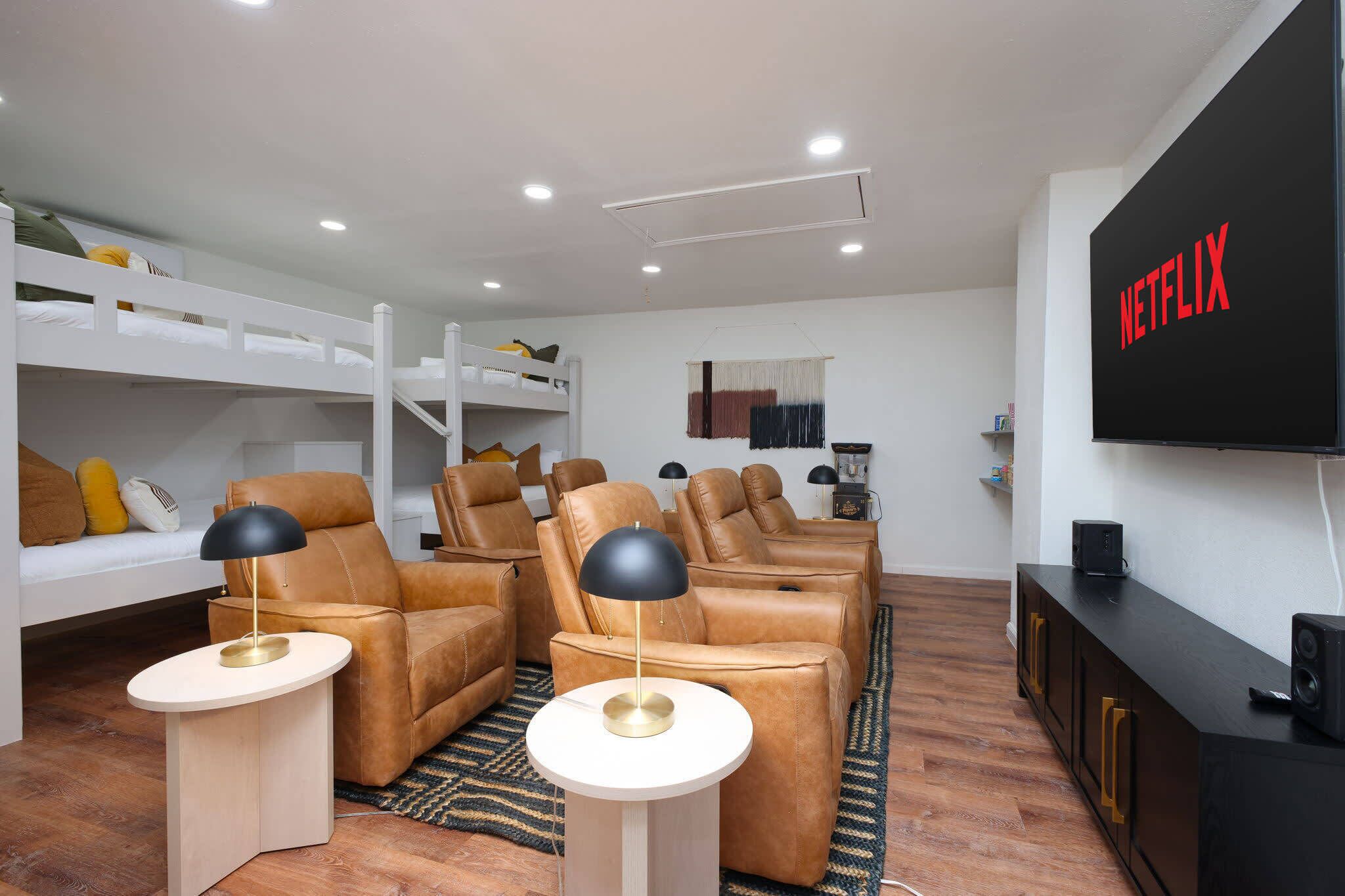 A modern living room with a sofa, chairs, a TV, and a bunk bed.