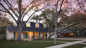 A two-story house with a dark roof, green shutters, and a well-maintained lawn. - Giddy Up Getaway: Pool, Hot Tub & Family Fun! (San Antonio)