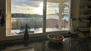 Eine Küche mit einem großen Fenster und Blick auf einen See und sanfte Hügel.