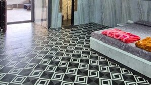 A hotel room with a geometric patterned floor, a bed with a patterned bedspread, and a view of the outdoors through a large window. - HM Villas (Paud)