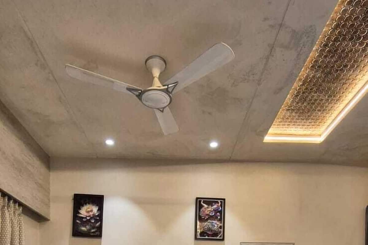 Quarto com uma cama grande, ventilador de teto, paredes de mármore e obras de arte.