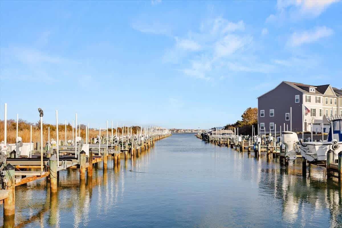 A marina with boats docked along a calm waterway, surrounded by buildings.