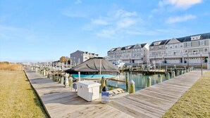 A marina with a wooden dock, a covered seating area, and a row of multi-story buildings. - Harborview Retreat Mansion (Ocean City)