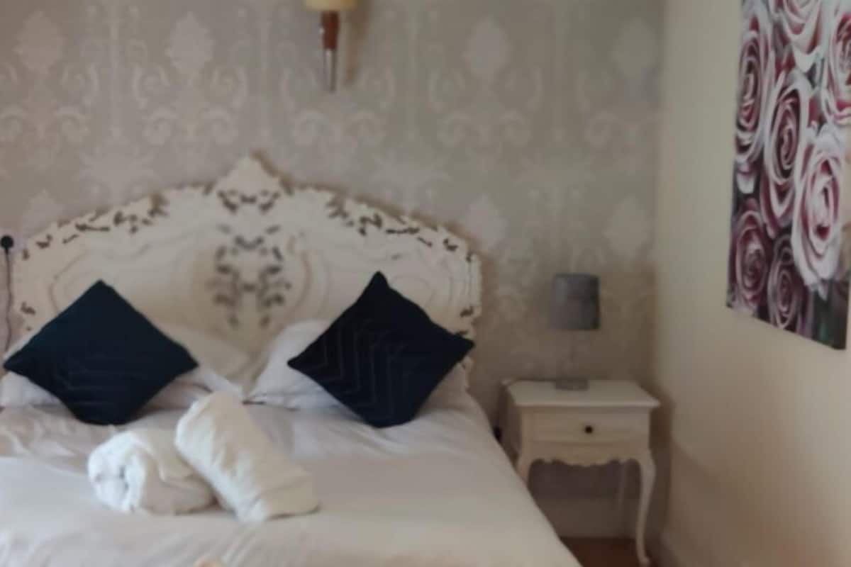 Een slaapkamer met een groot bed, twee nachtkastjes en een wand met bloemenmotief.