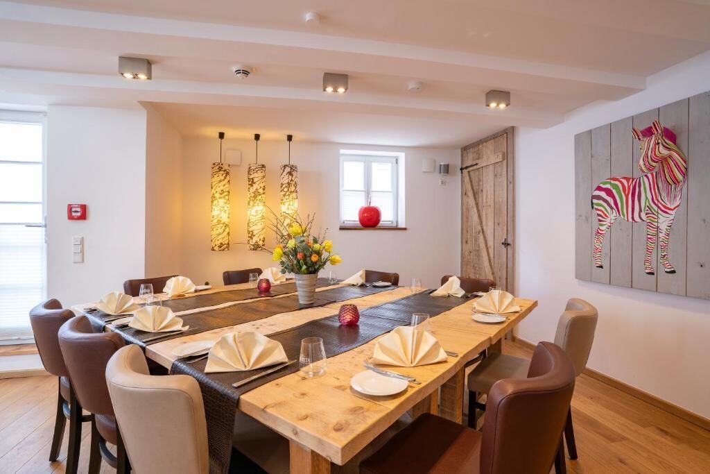 A dining area with a long wooden table, chairs, and modern pendant lights.