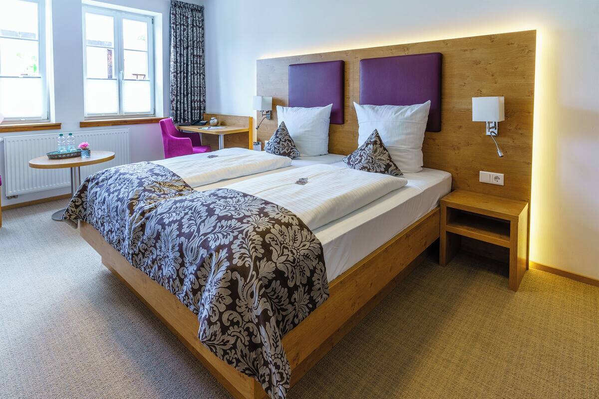 A double bed with a patterned bedspread, a wooden headboard, and two bedside tables with lamps.