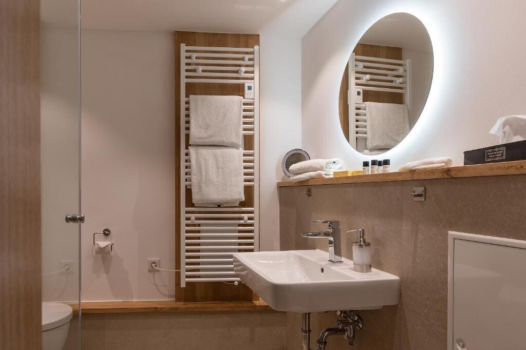 A modern bathroom with a glass shower enclosure, a white sink, and a mirror with a wooden frame.