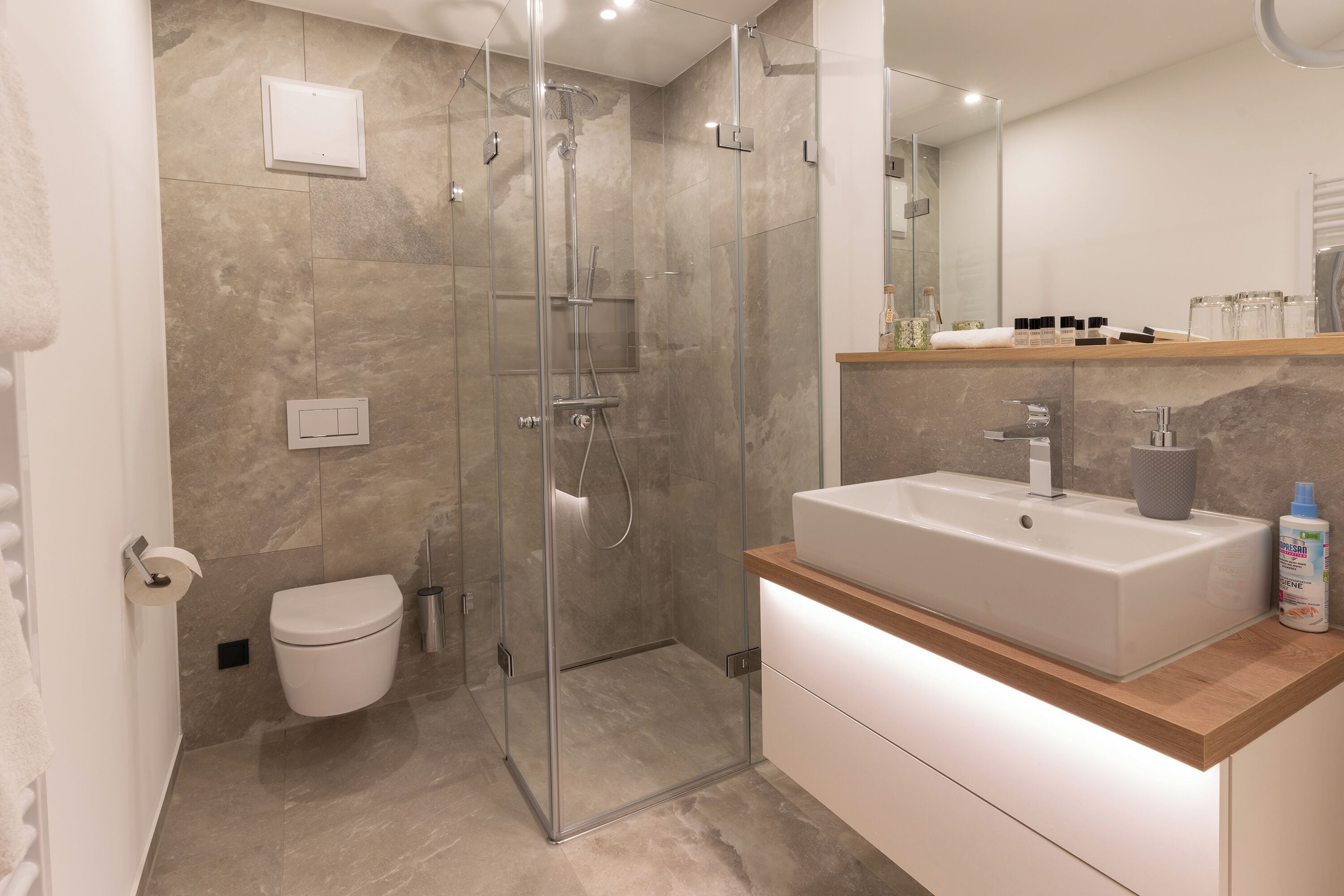 A modern bathroom with a glass-enclosed shower, a white sink, and a wooden countertop.