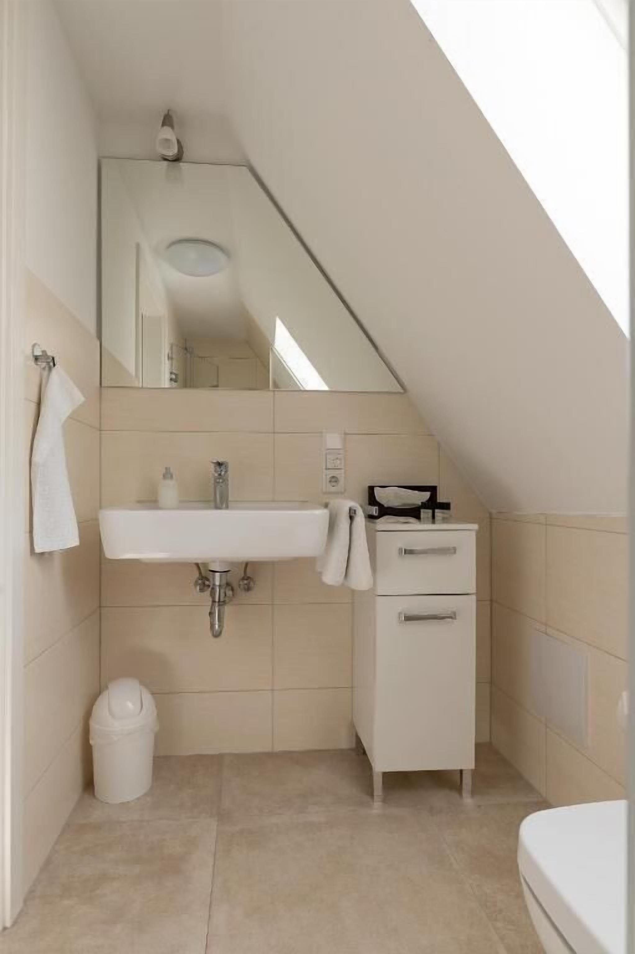 A small, modern bathroom with a white sink, mirror, and storage cabinet.